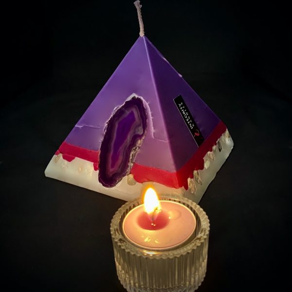 Tutankhamon: smallest in our pyramid range and burning over 90 hours. Deeply relaxing, essential oils of Lavender, Patchouli, Citrus, Marjoram, Jojoba, Geranium and Chamomile are presented in a meditative shade of purple. A band of magenta sits above a white base embedded with river pebble. As your pyramid candle burns, the flame illuminates an Agate slice, revealing the stone's unique variegated pattern, and leaves you with gorgeous keepsake.