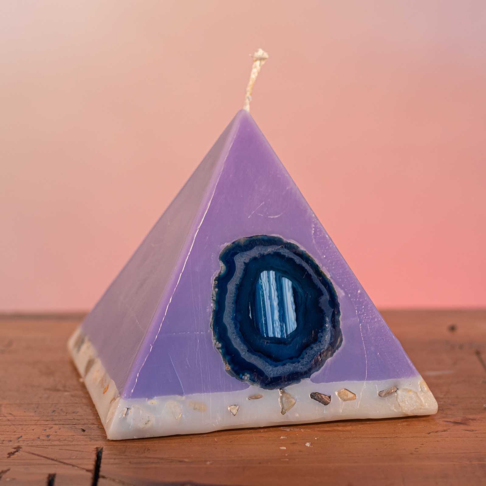 As your pyramid candle burns, the flame illuminates the Agate, revealing the stone's unique variegated patterns, and leaves you with a gorgeous keepsake. Deeply relaxing, this blend of essential oils includes Lavandula Angustifolia, Patchouli, Citrus, Marjoram, Jojoba, Geranium and Chamomile. A meditative shade of purple, the range features a white base embedded with river stone. As your pyramid candle burns, the flame illuminates the Agate, revealing the stone's unique variegated patterns, and leaves you with a gorgeous keepsake. Deeply relaxing, this blend of essential oils includes Lavandula Angustifolia, Patchouli, Citrus, Marjoram, Jojoba, Geranium and Chamomile. A meditative shade of purple, the range features a white base embedded with river stone.
